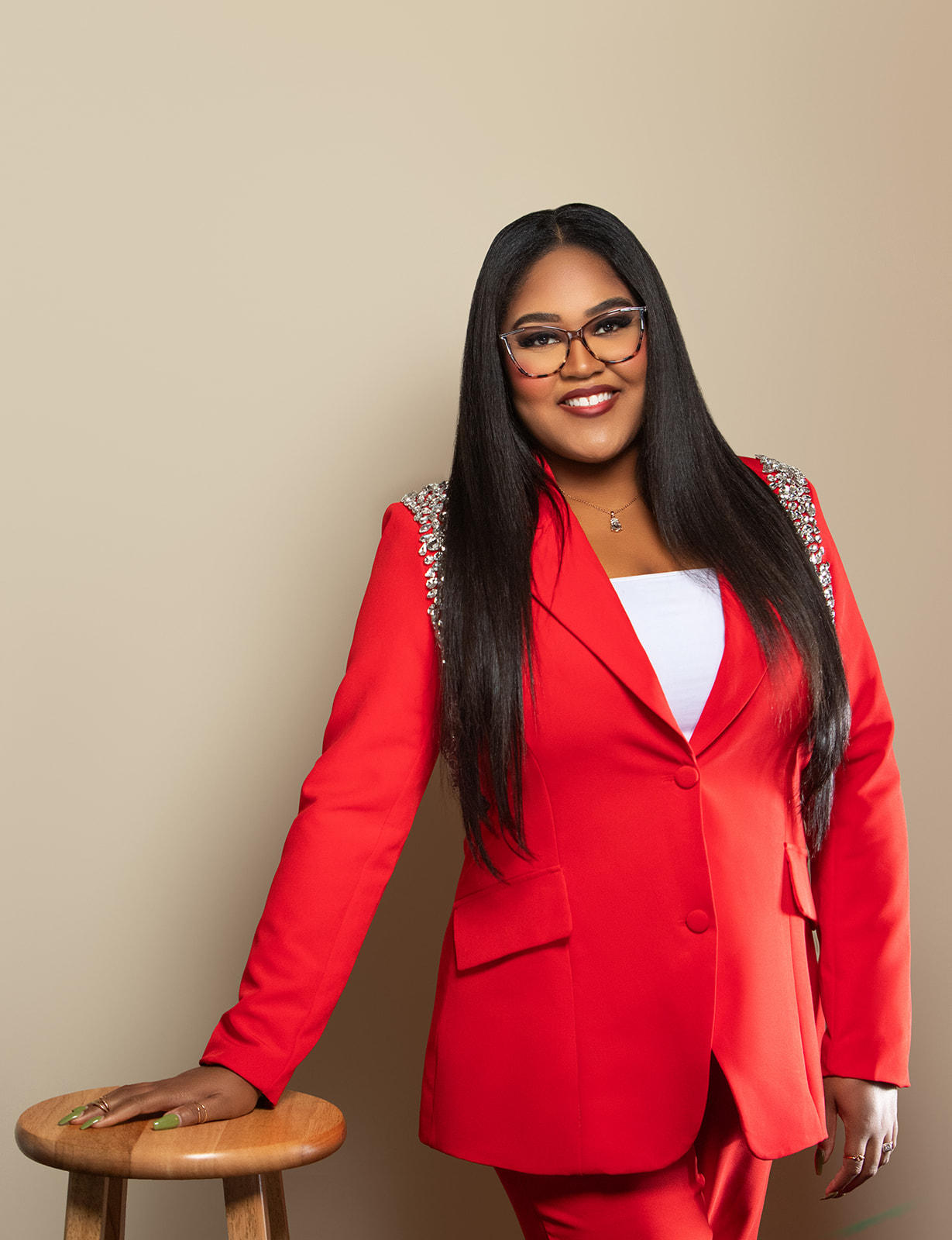 alexis m lott in red blazer creme background facing forward smiling with long black hair